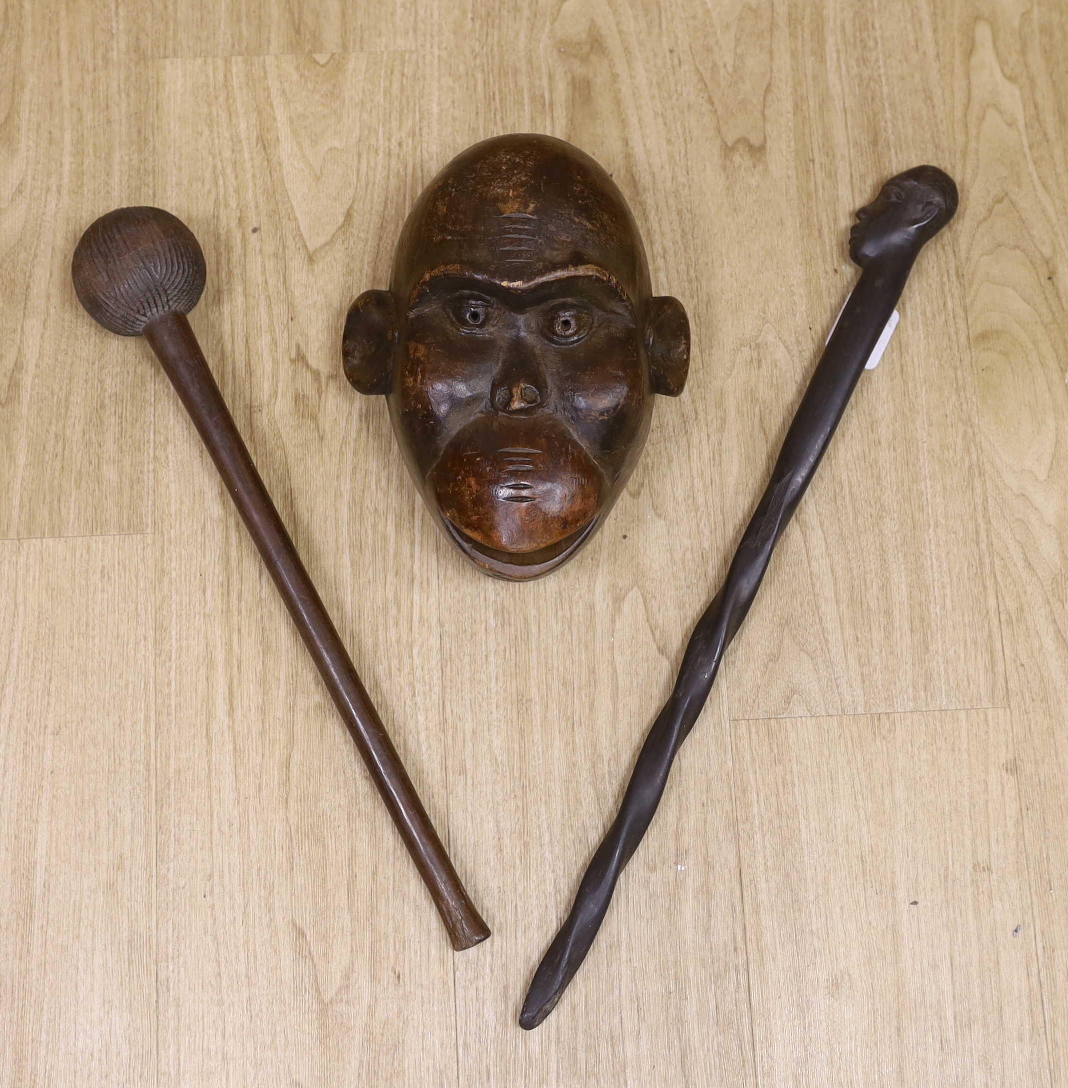 A tribal mask, a Knobkerrie and stick with carved head, stick 62.5cm